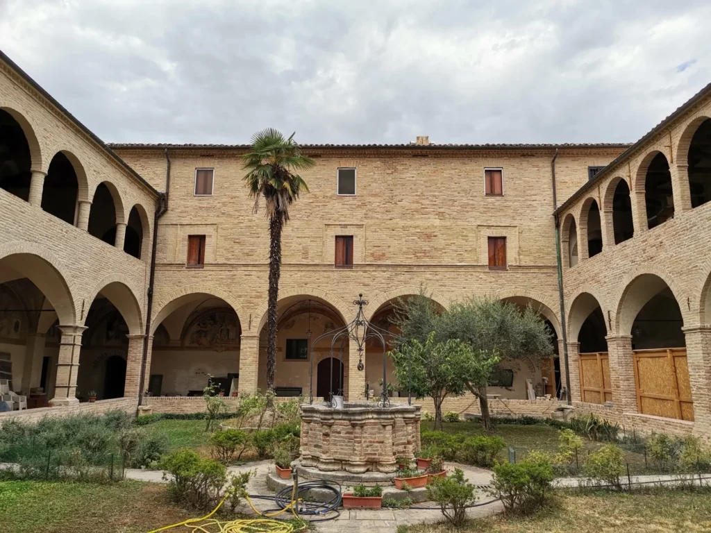 Chiostro del monastero con il pozzo, la palma e i portici ad arco