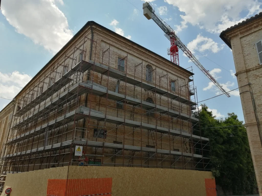Facciata in laterizio del monastero di San Marco ricoperta da ponteggi, con la gru di cantiere